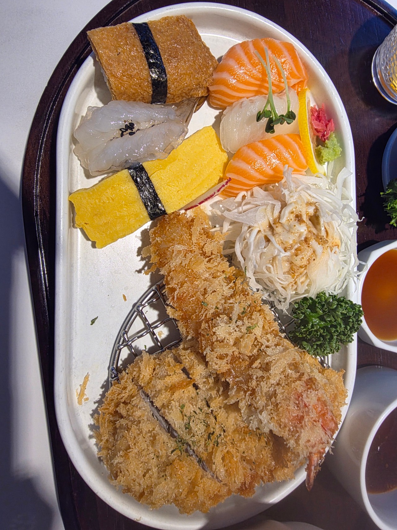 위에서 내려다본 일식 정식 한 상 플랫레이. 네모난 검은 접시 위에 두툼하게 썰린 수제돈까스, 계란·유부·연어·광어 초밥 네 피스, 단면이 보이